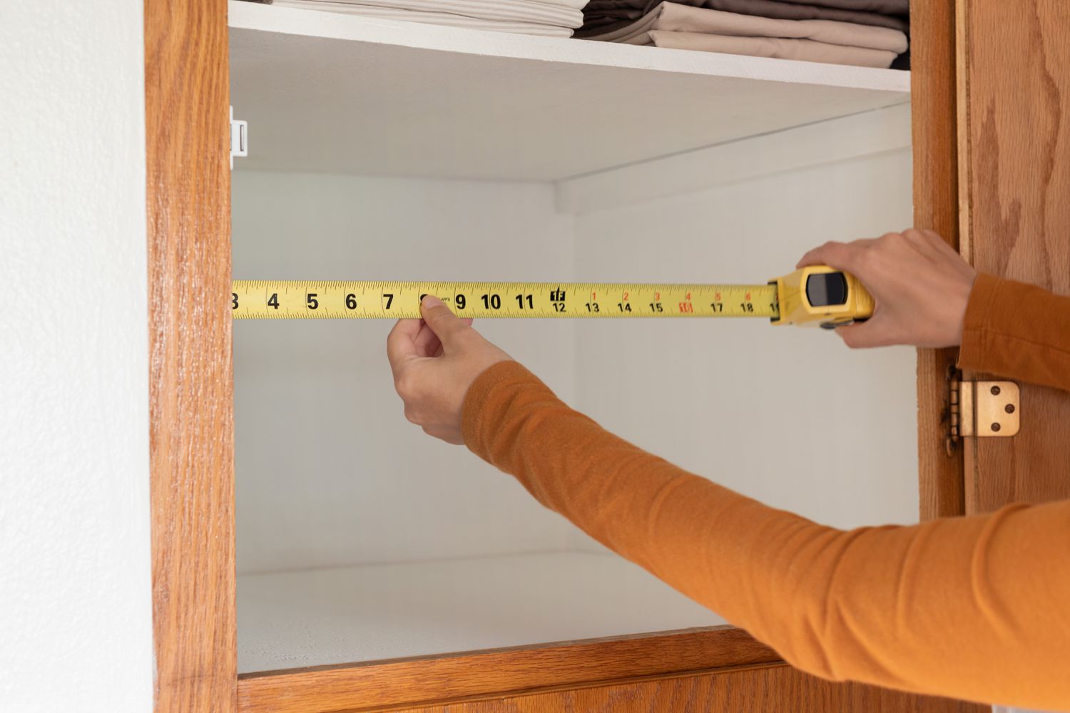 Storage area for towels being measured with yellow measuring tape