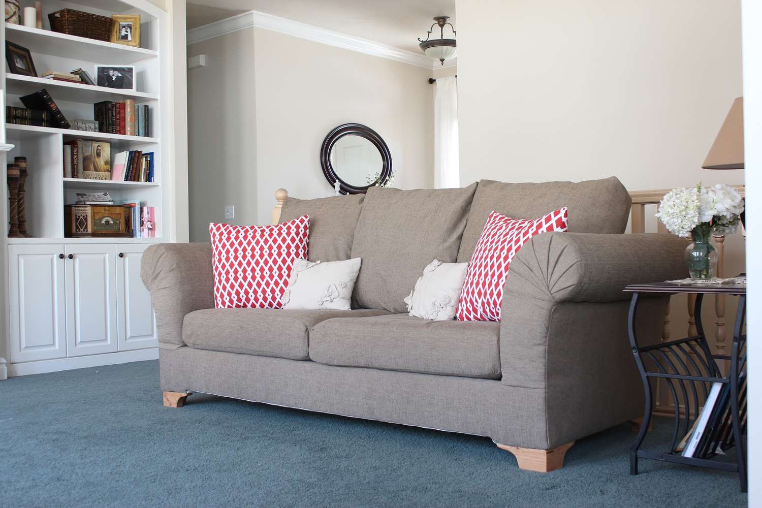Un cómodo sofá marrón con cojines rojos.