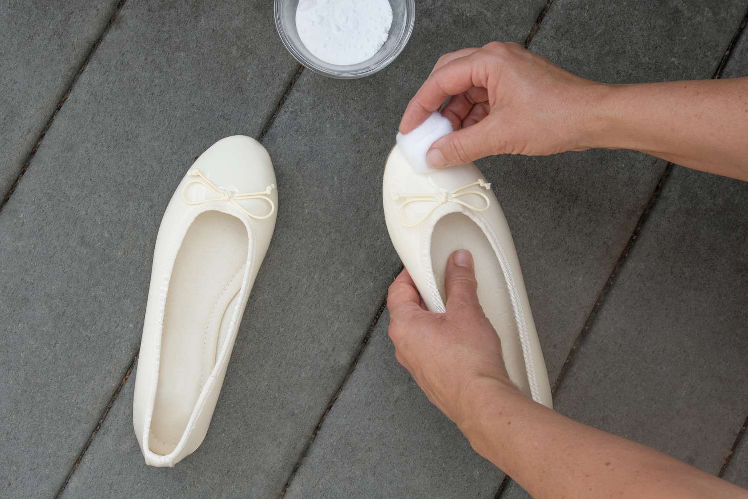 Bola de algodão limpando a parte superior de sapatos brancos de couro envernizado com removedor de polimento de correio