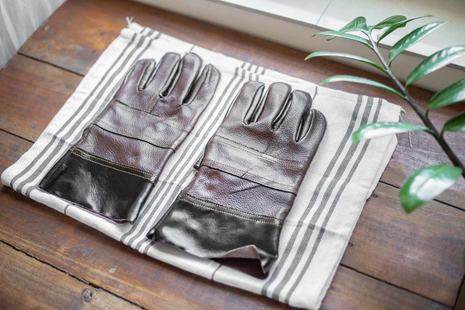 Lederhandschuhe zum Lufttrocknen auf ein gestreiftes Handtuch gelegt