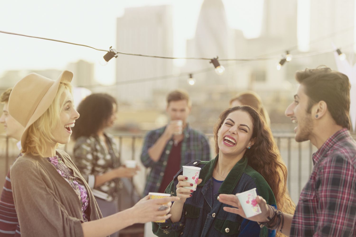 Junge erwachsene Freunde lachen und trinken auf einer Dachterrassenparty