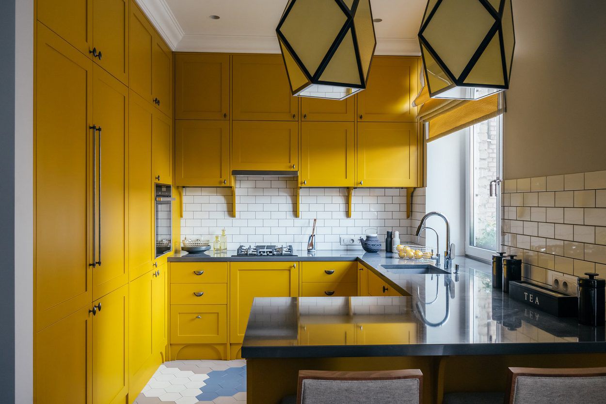 Modern yellow kitchen cabinets with white backsplash.