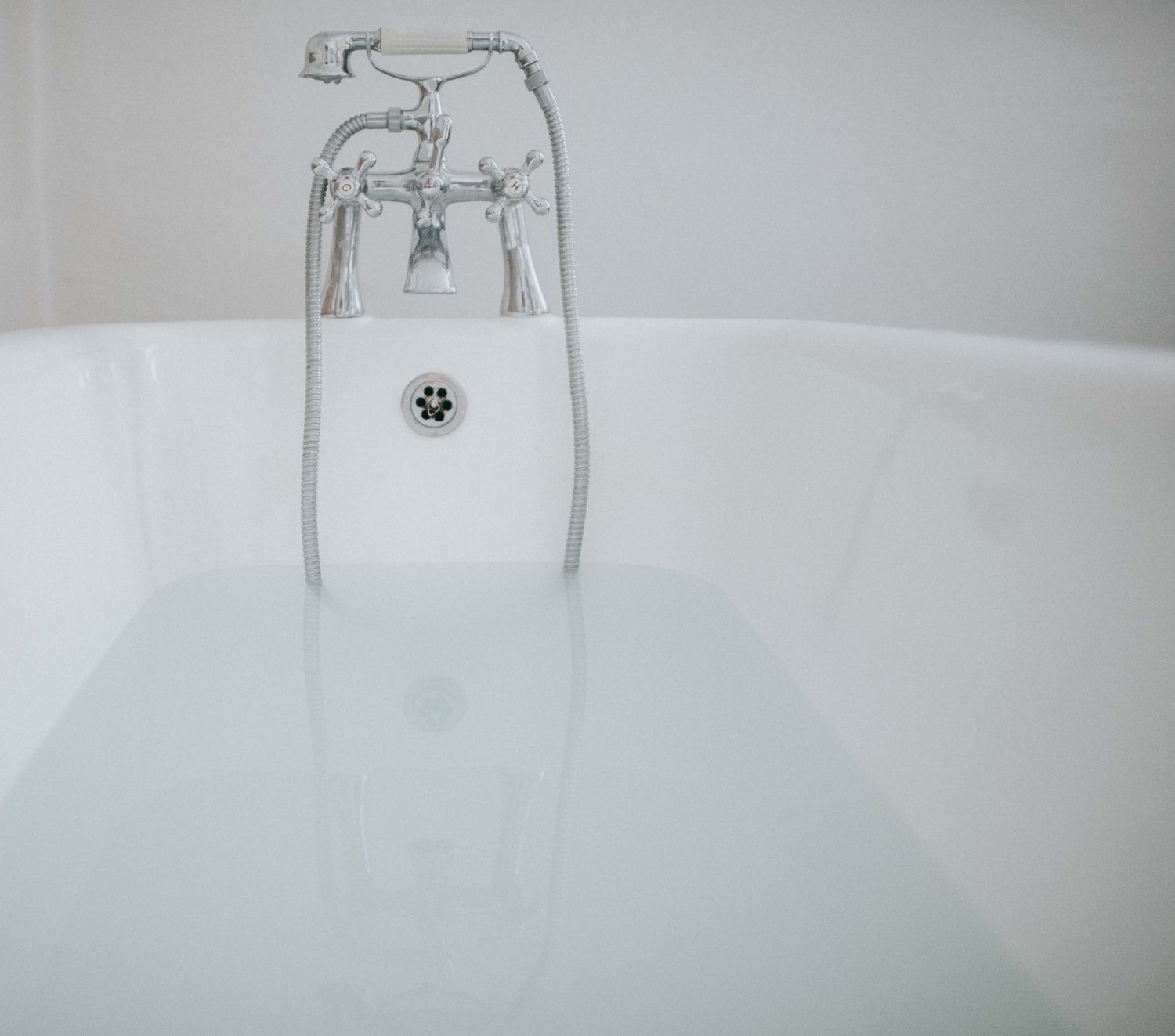 halbgefüllte Wanne mit Blick auf Wasserhahn und Überlaufdichtung