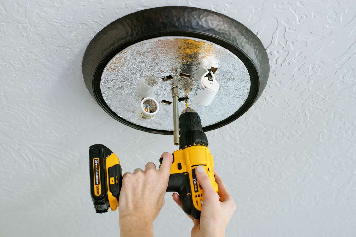 Cordless drill removing light fixture from ceiling