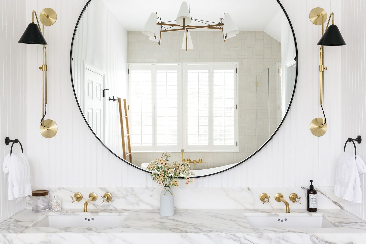 Badezimmer mit weißem Marmorwaschbecken und großem runden Spiegel