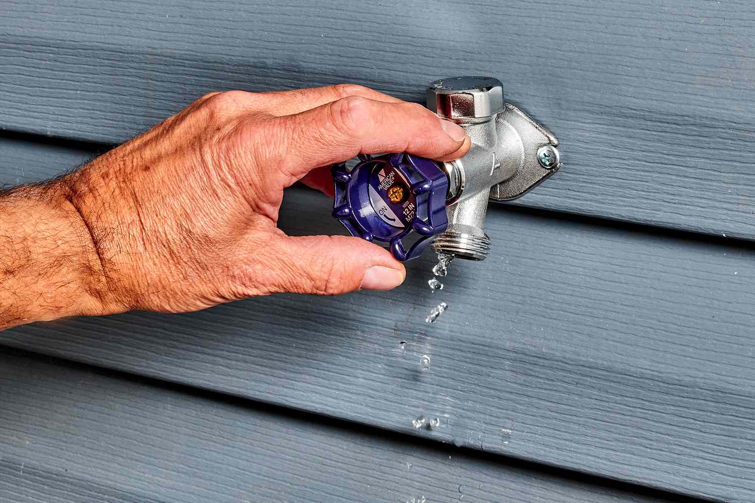 Robinet antigel avec bouton bleu tourné et eau qui coule 