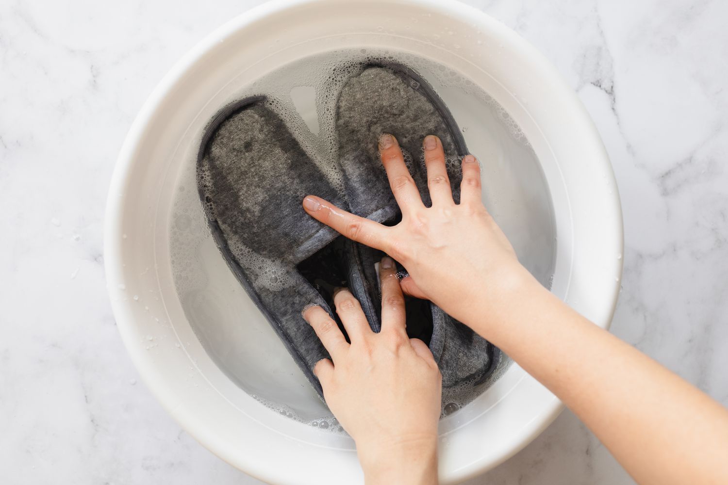 Stoffpantoffeln handgewaschen im Eimer mit Seifenwasser