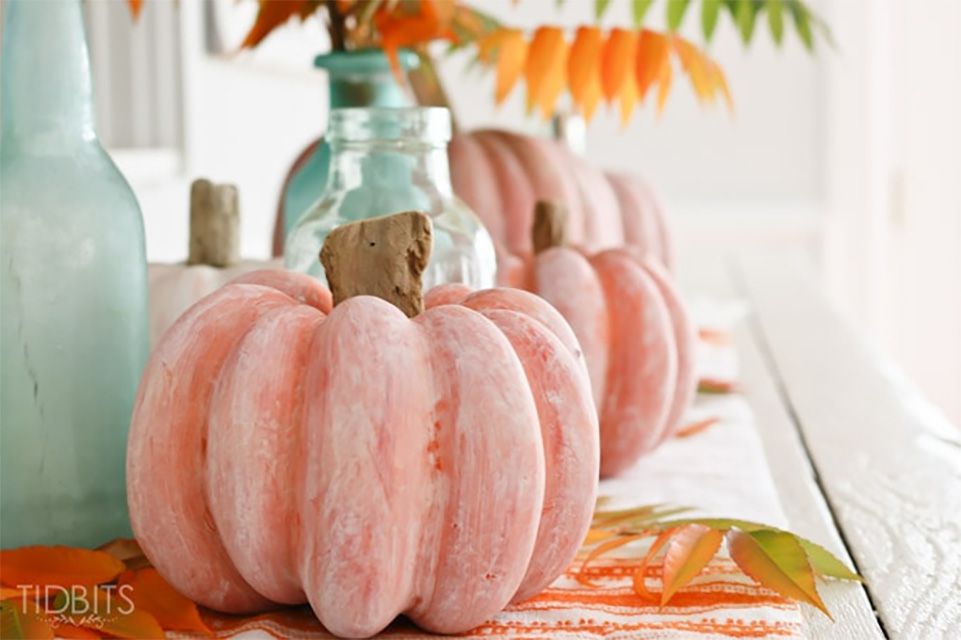 Una calabaza naranja lavada de blanco sentada en una mesa