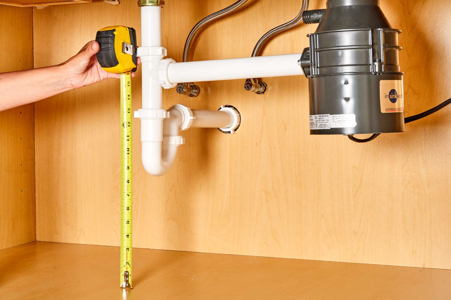 Fita métrica amarela calculando medidas sob o encanamento da pia da cozinha