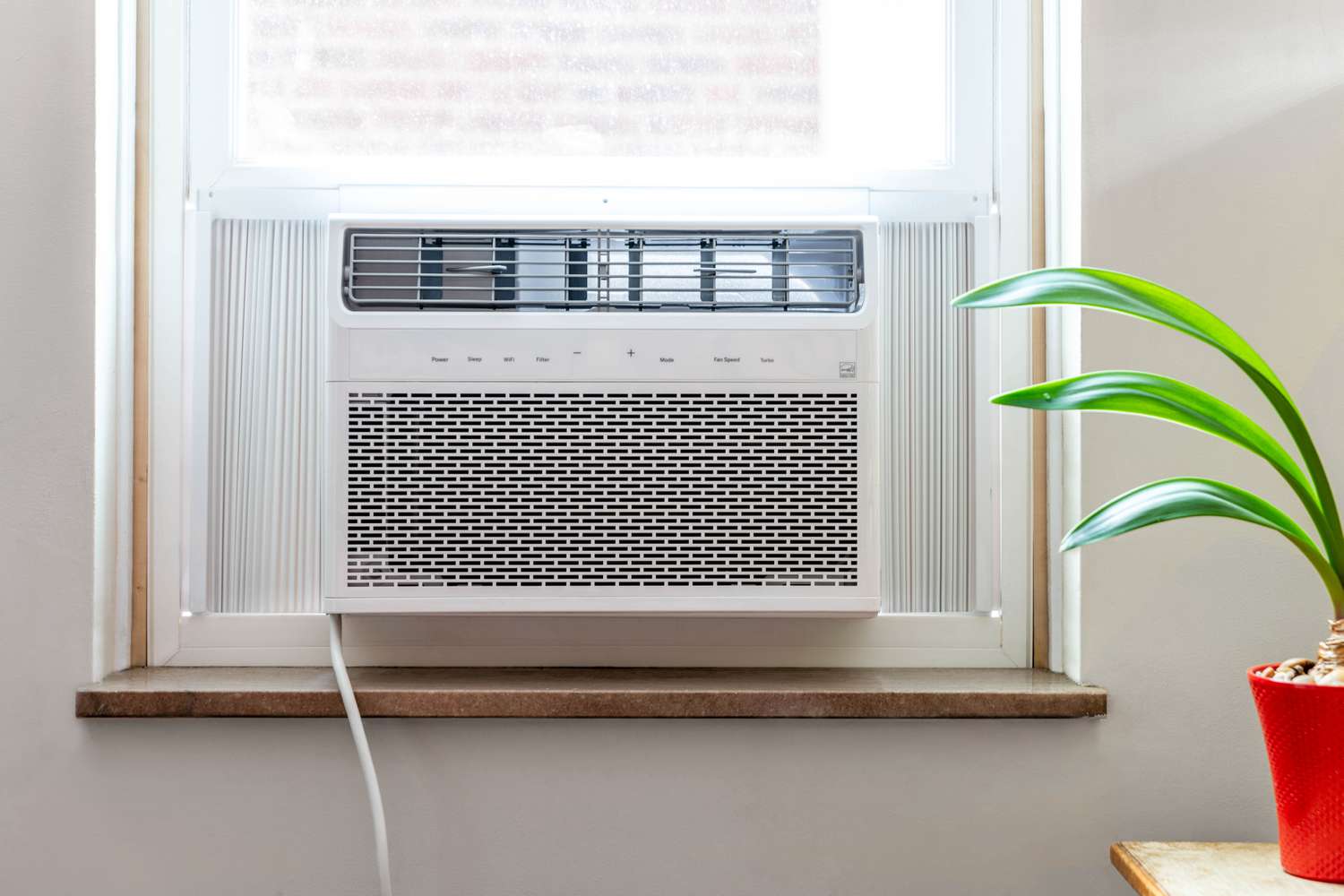 Fenster-Klimaanlage neben Zimmerpflanze
