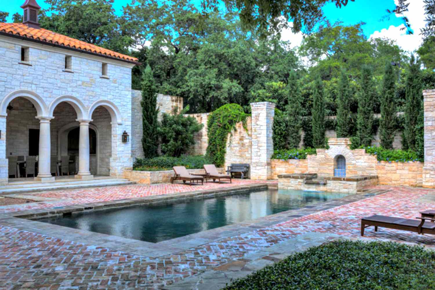 Mediterrane Pool-Designs mit Steinstegen, Säulenveranda und Liegestühlen.