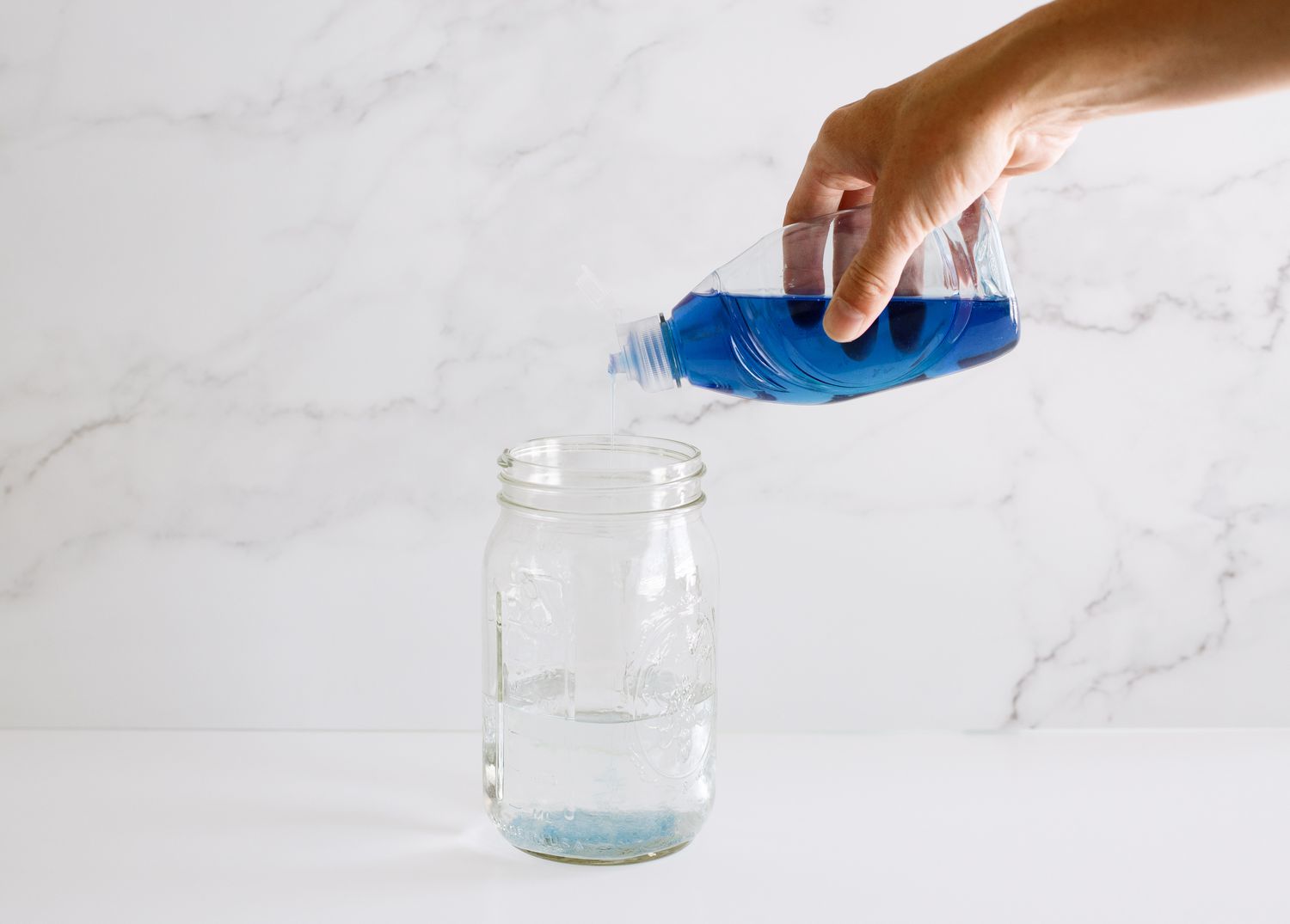 Líquido lavavajillas añadido al frasco de cristal con agua