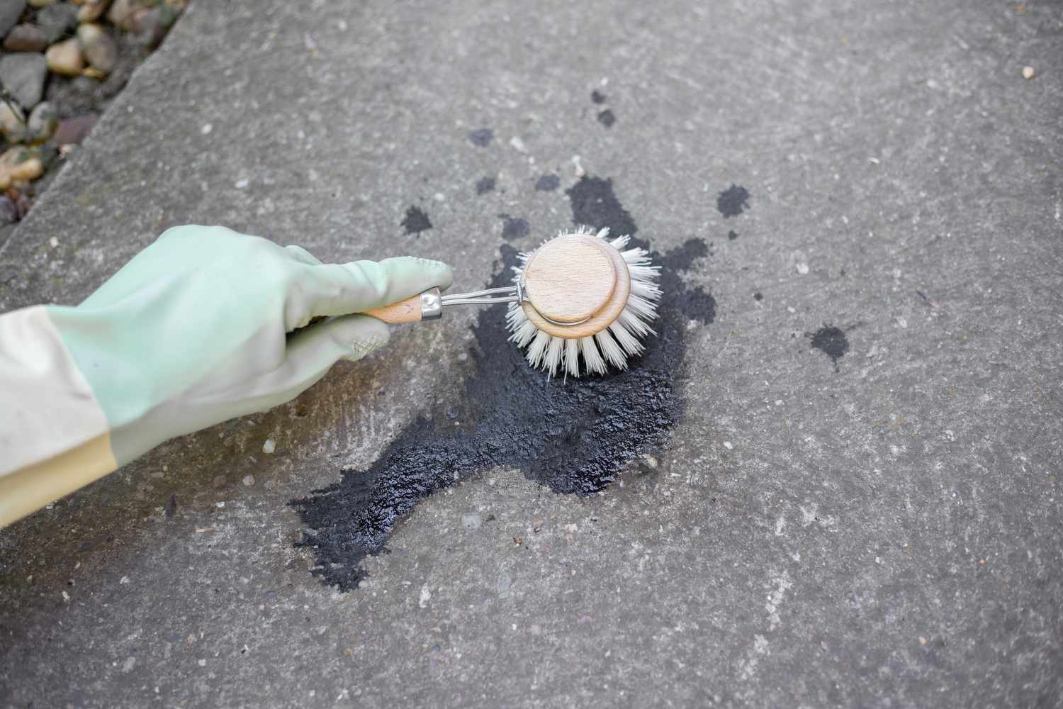 Frotando disolvente en la mancha de aceite con un cepillo de nailon y guantes