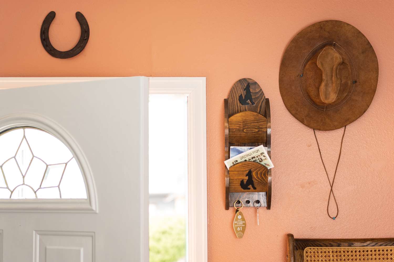 Dark horseshoe hanging over white door next to cowboy hat and letter holder closeup