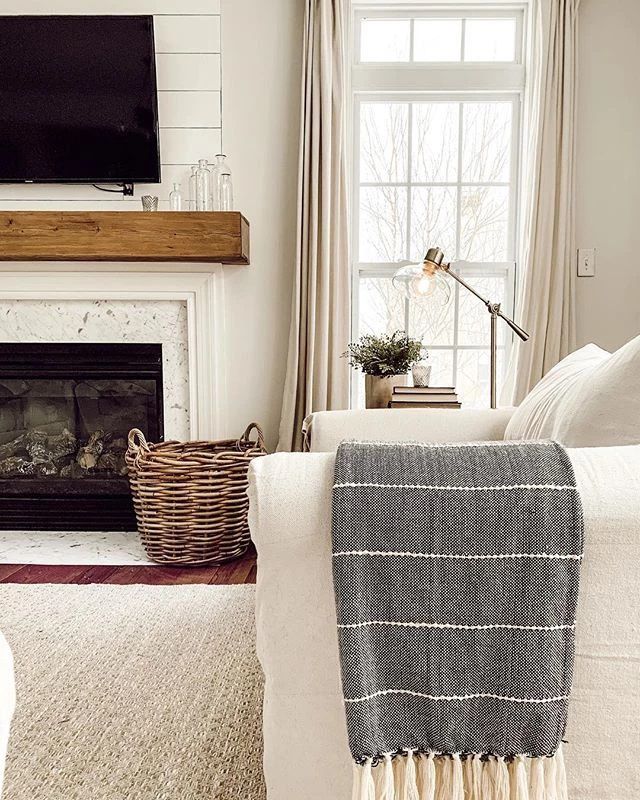 Eine weiße Couch mit einer grau gestreiften Decke über dem Arm.