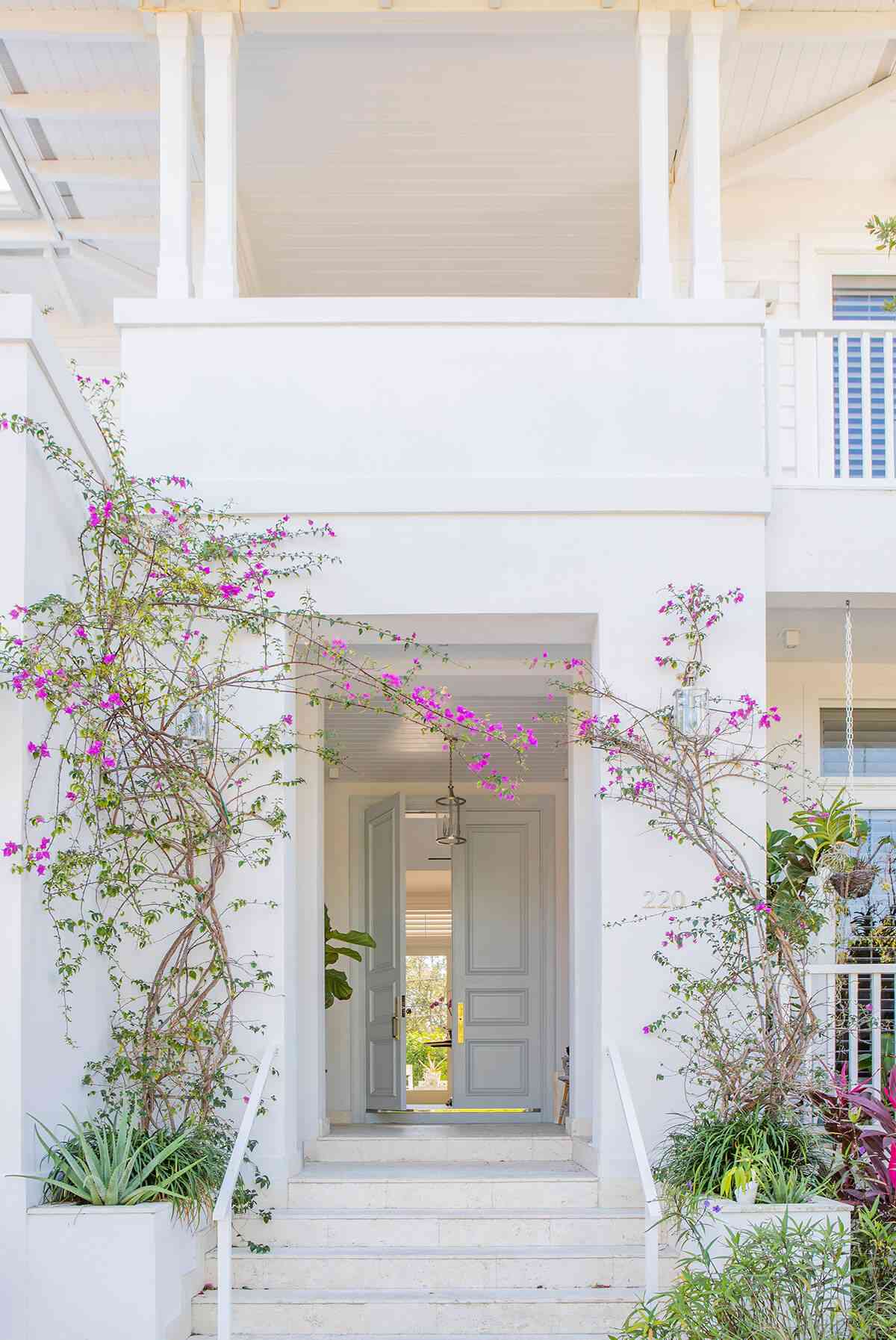 Ein weißes Haus mit einer hellblauen Eingangstür und Frühlingsblumen