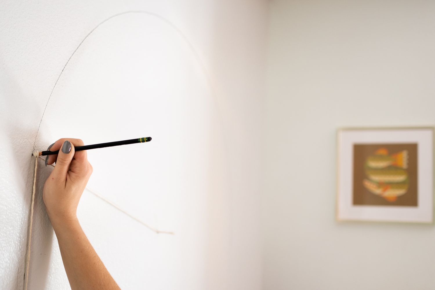 Forma de arco traçada na parede com lápis e barbante para medição