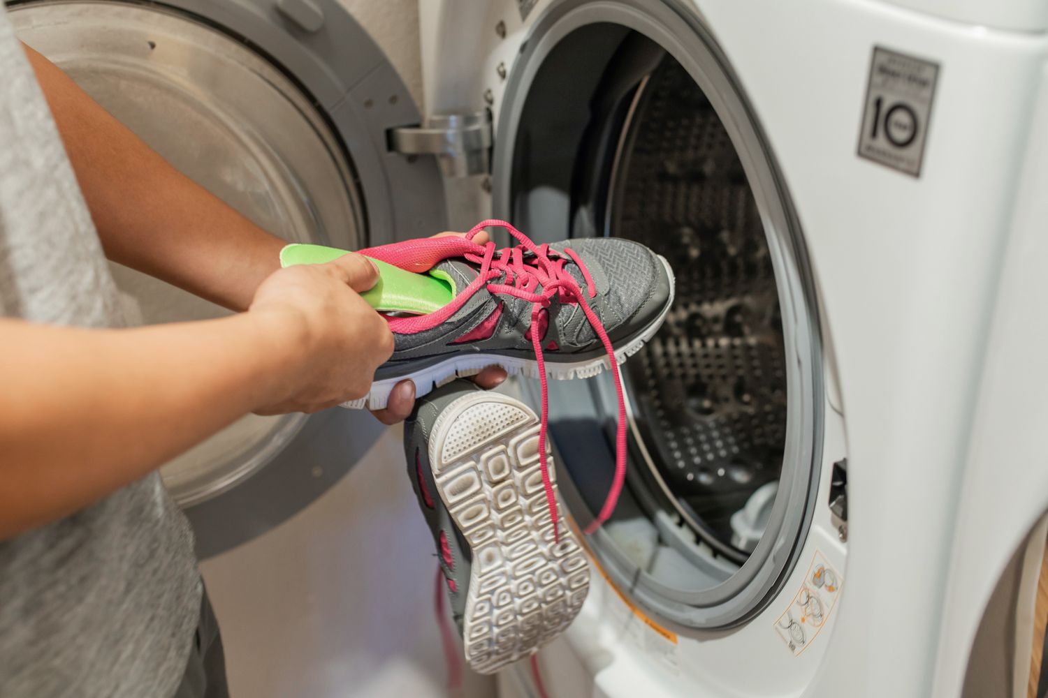 person tossing sneakers into the washer