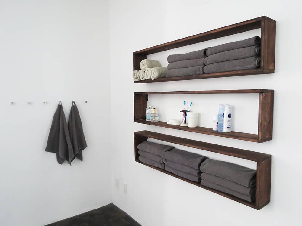 Drei lange Holzregale an einer weißen Badezimmerwand
