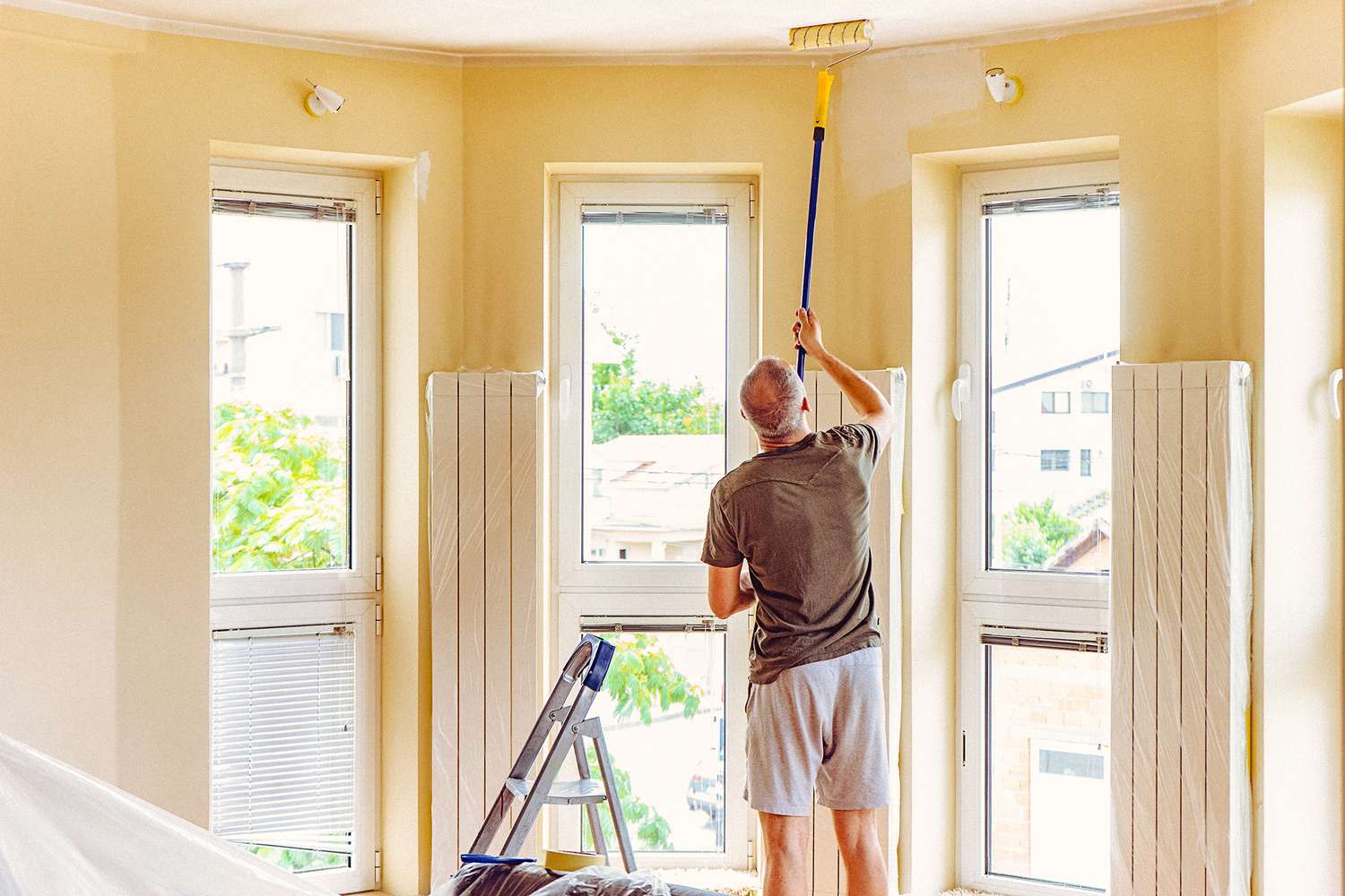 Homem pintando o teto do quarto