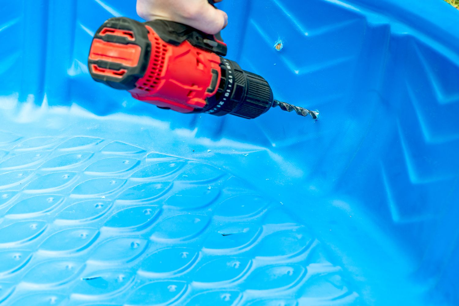 Electric drill poking holes in side of kiddie pool for drainage