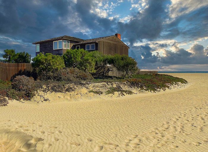 Casa de playa con arbustos y valla de madera