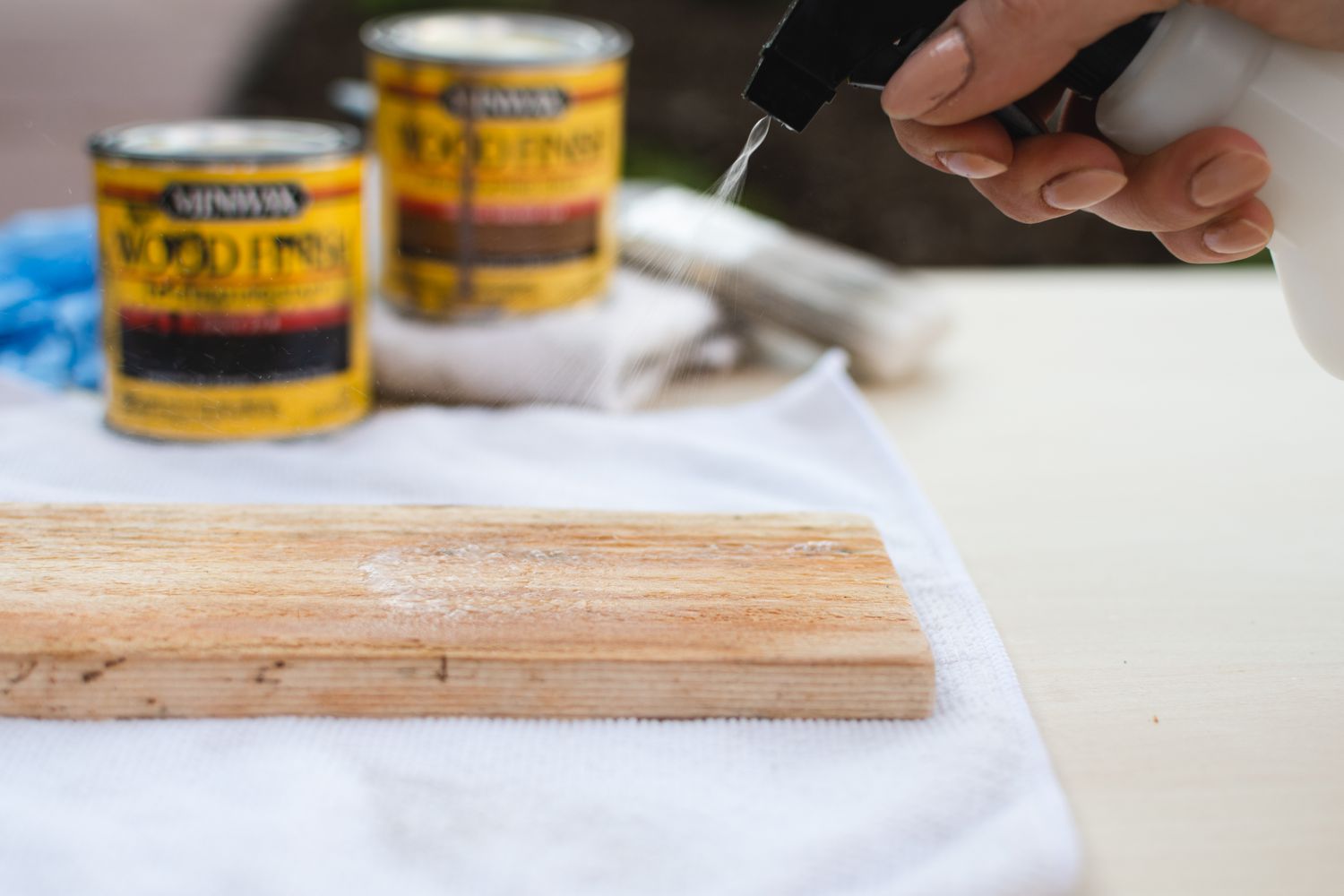 Mit Wasser bespritzte Holzbohle vor Eimern mit Farbbeize