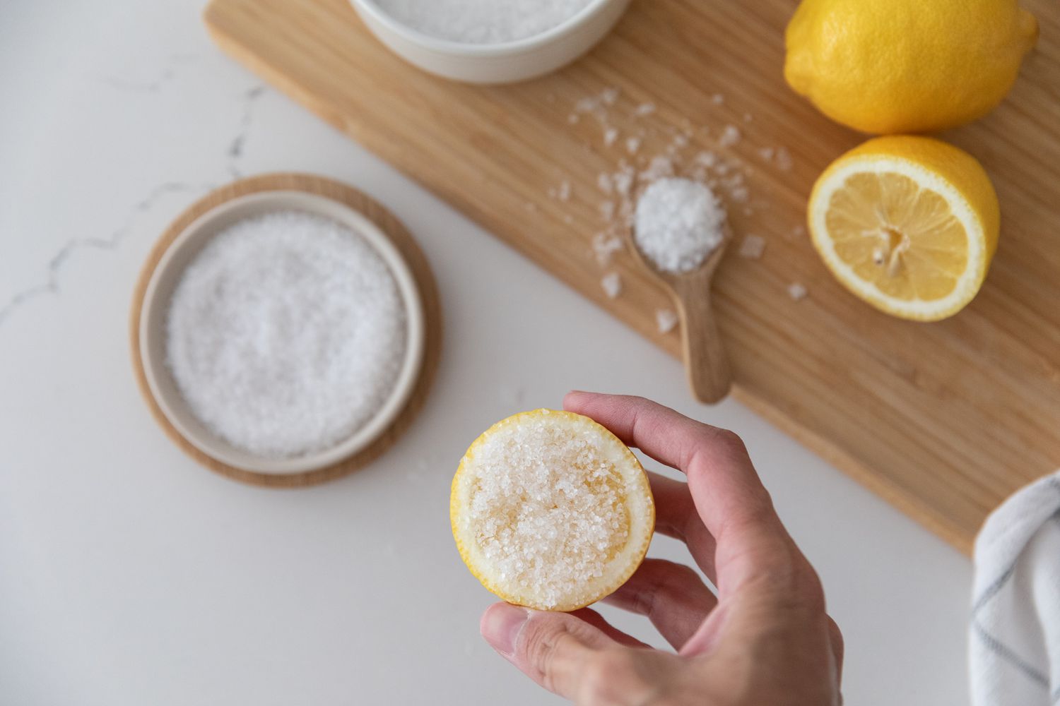 Salz auf Zitronenhälfte gerieben über Schüssel mit Salz und geschnittenen Zitronen