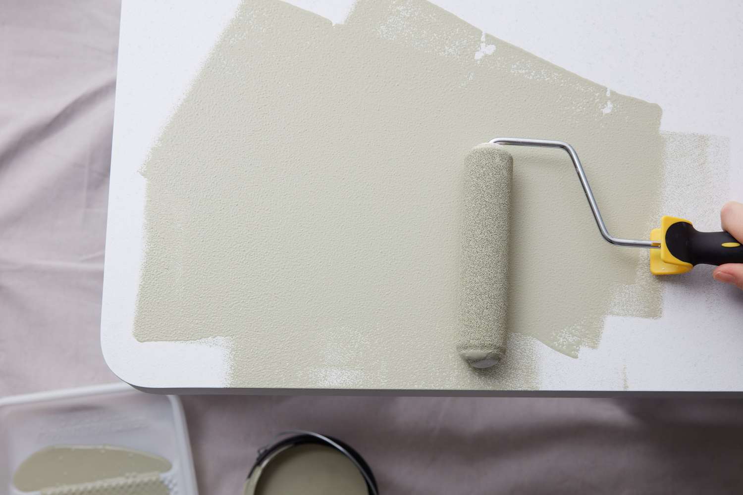 Cream paint on paint roller going over laminate surface