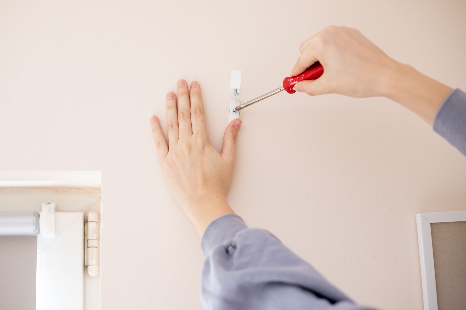 Kopfschienenhalterungen mit Schraubendreher in die Wand geschraubt