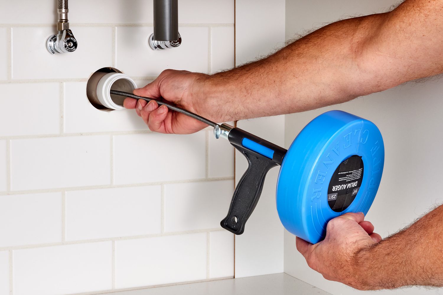 Handheld auger handle turned inside sink drain for unclogging