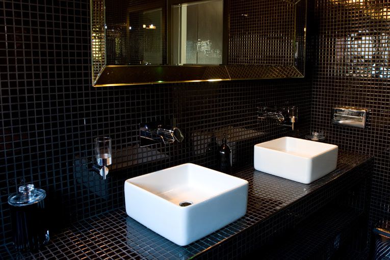 Schwarzes, quadratisch gefliestes Bad mit weißem Akzent-Waschbecken