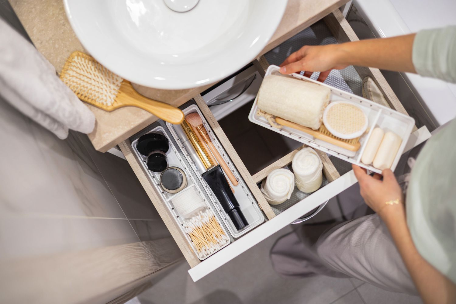 Mujer colocando insertos de cajón en el cajón del baño.