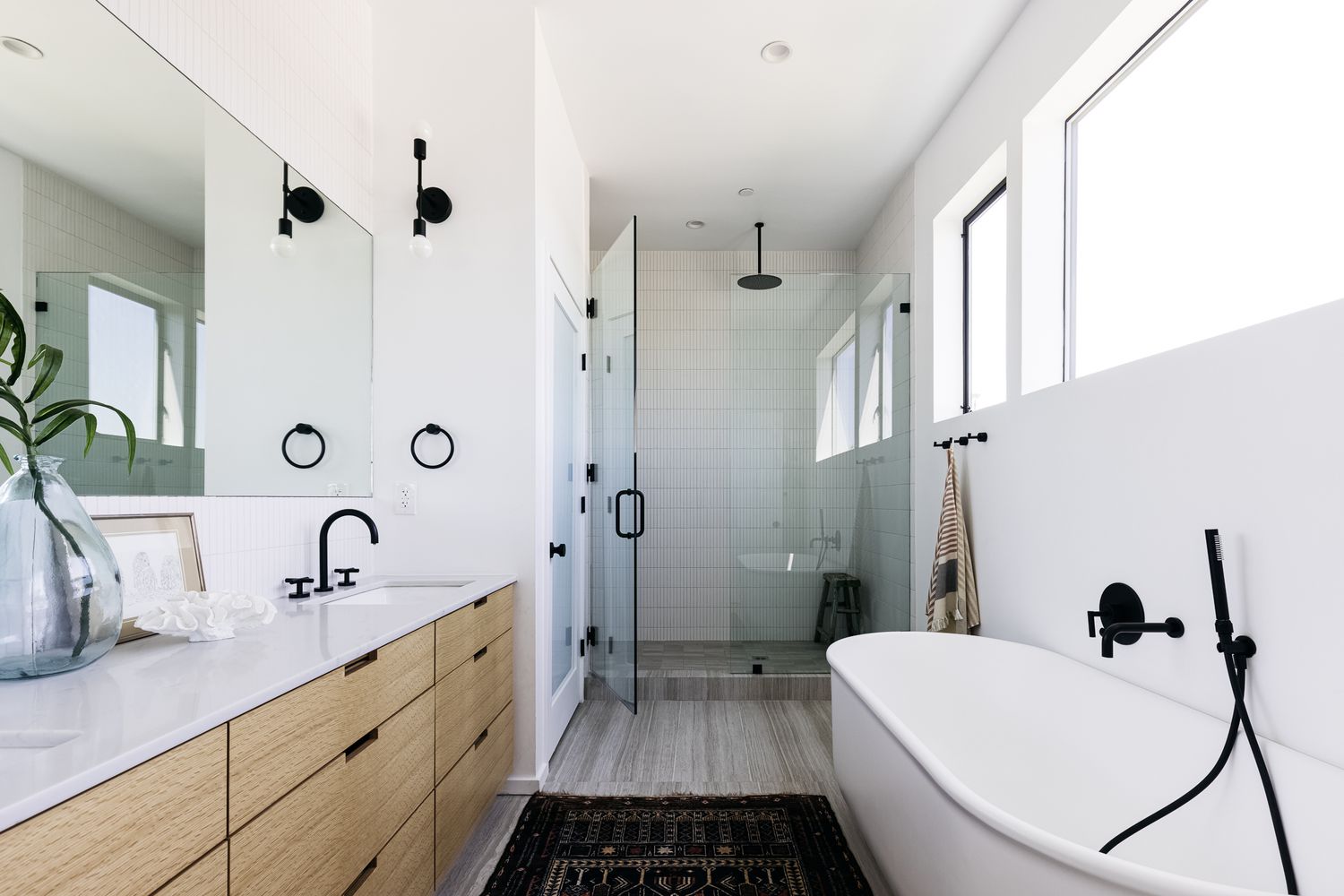 Modernes Bad mit freistehender Wanne, bodengleicher Dusche, hellen Fenstern und großem Spiegel