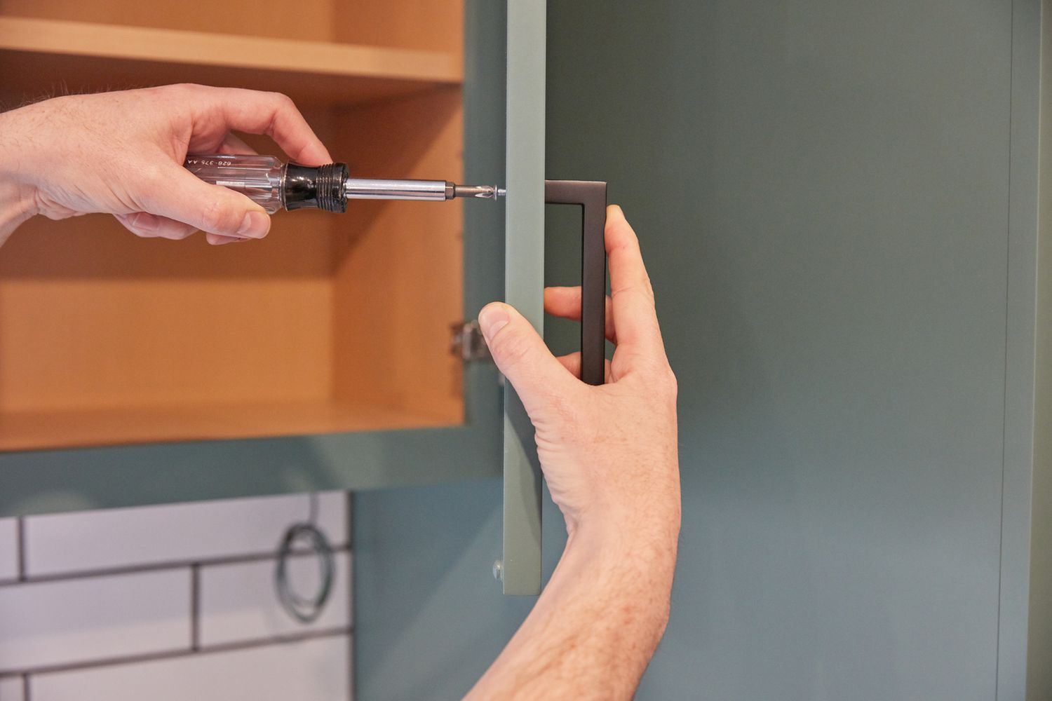 Kitchen cabinet black door handle reapplied with screwdriver