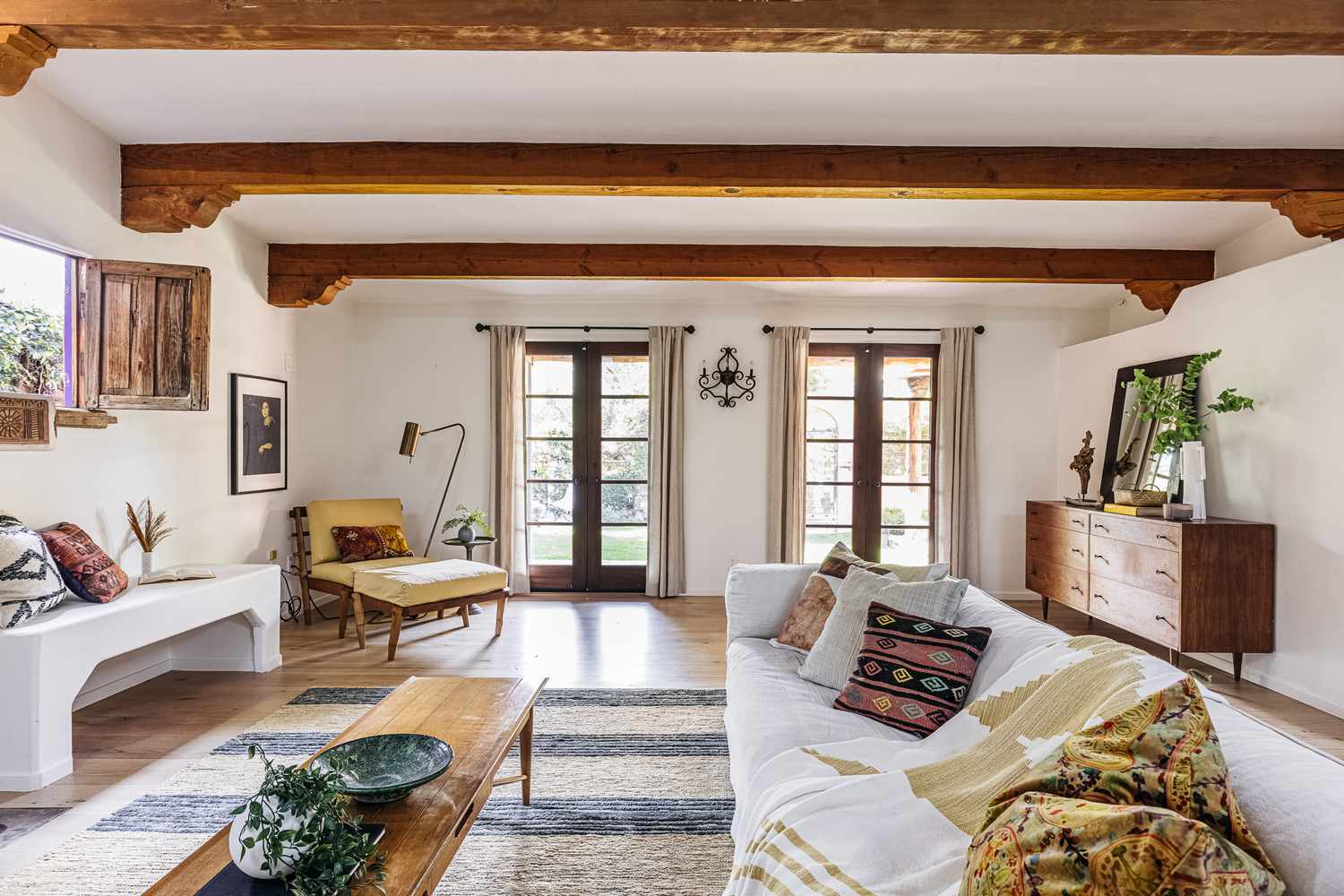 Sala de estar em estilo mediterrâneo com móveis de madeira, paredes brancas e almofadas estampadas