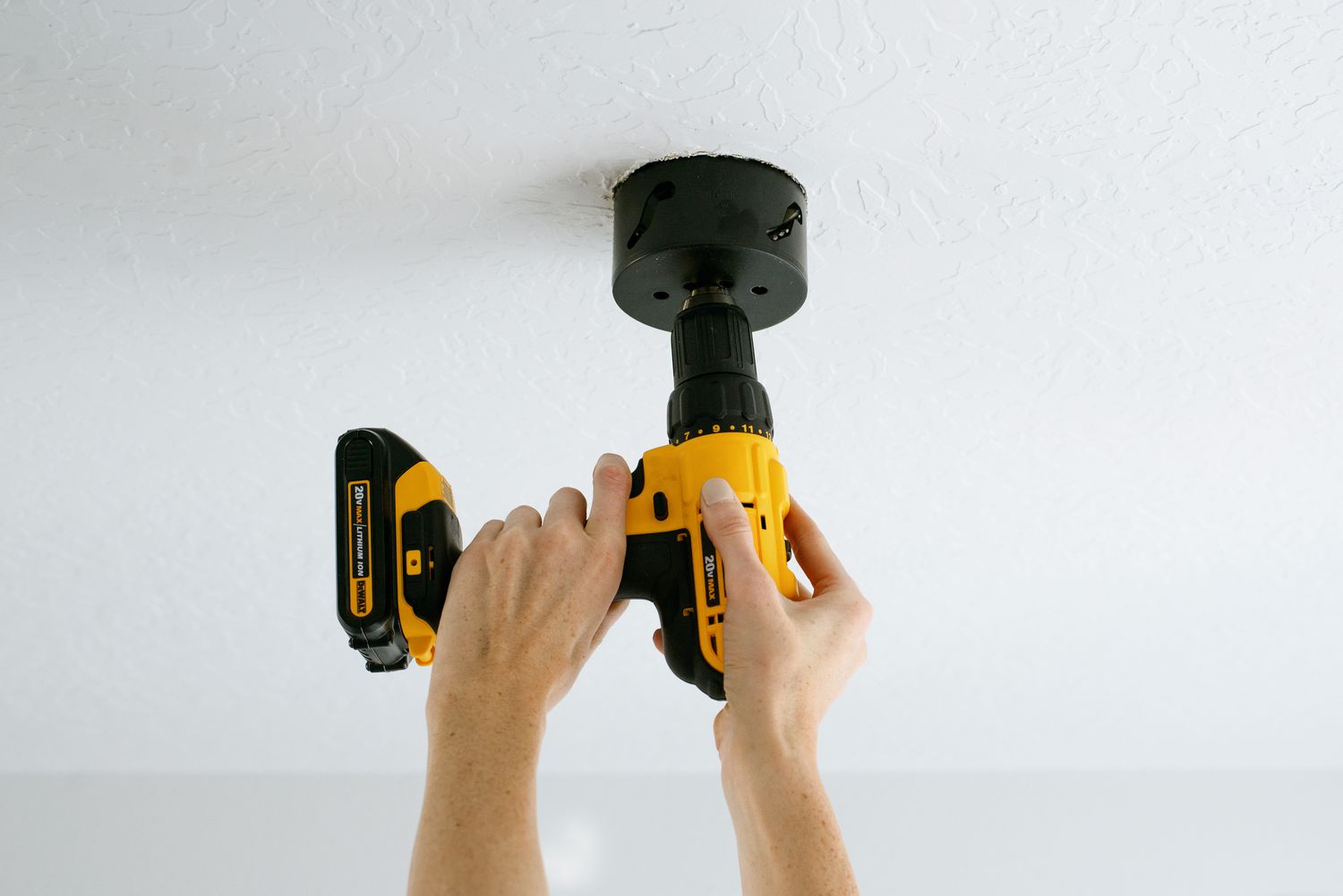 Cordless drill securing brace section to ceiling