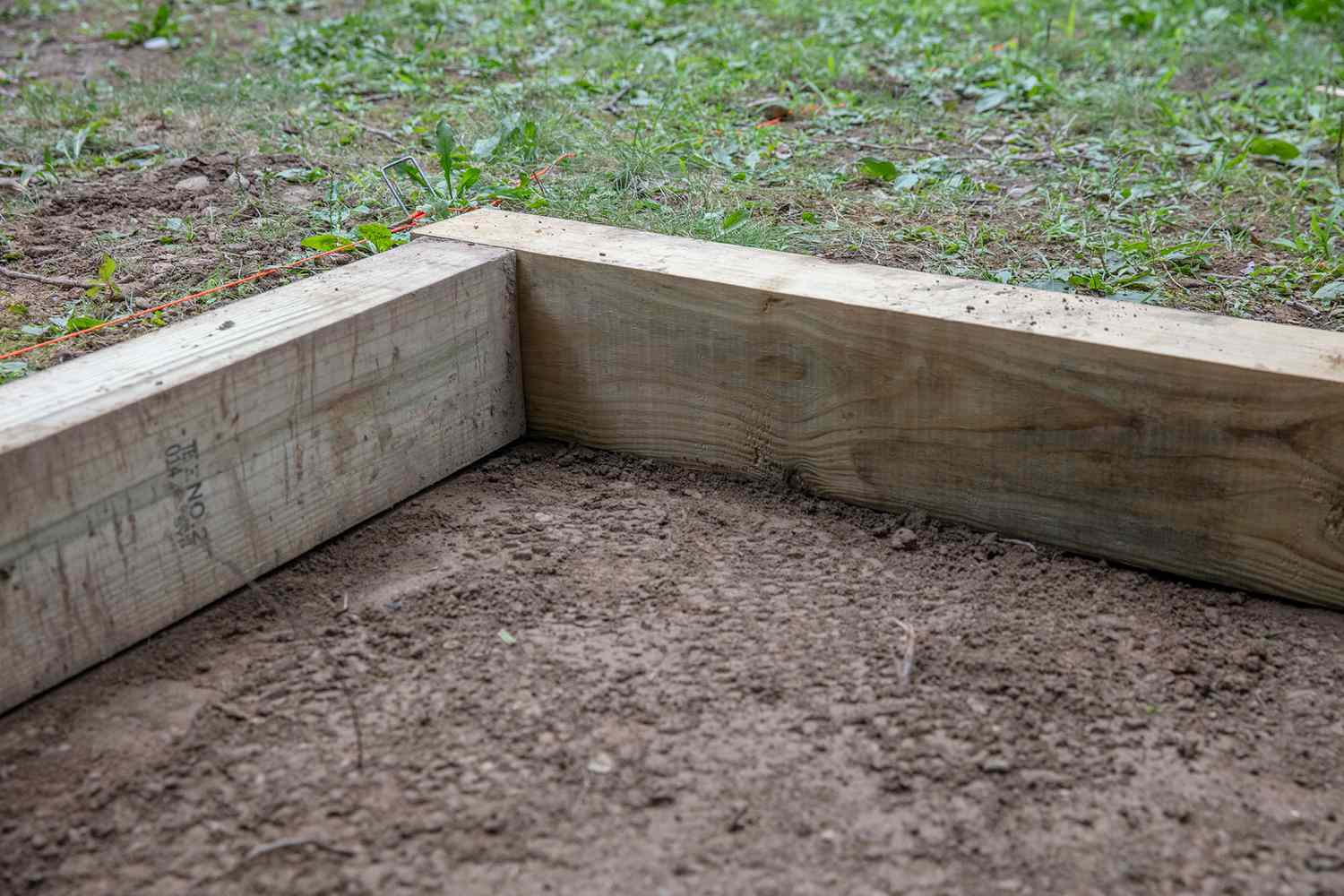 Rahmenhölzer auf geharktem Boden für Erbsenkies-Terrasse ausgelegt