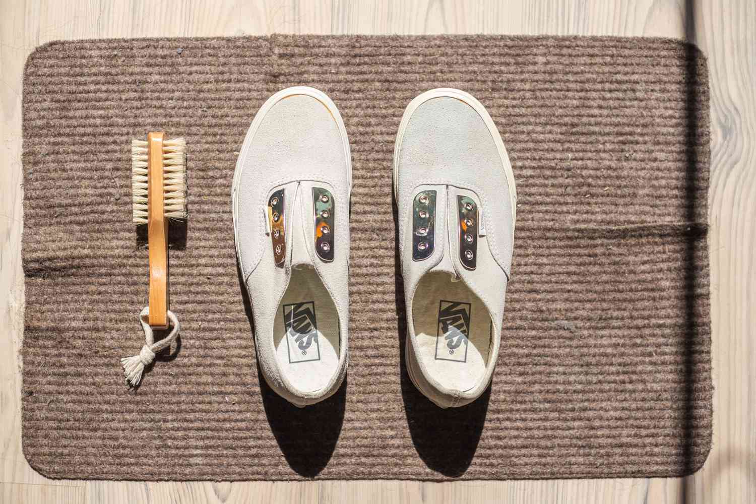 White suede Vans placed on brown rug to air dry in sunlight