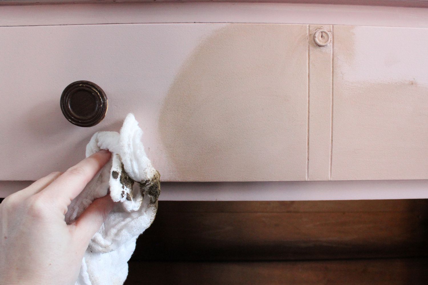 A hand buffing out wax on a chalky paint dresser
