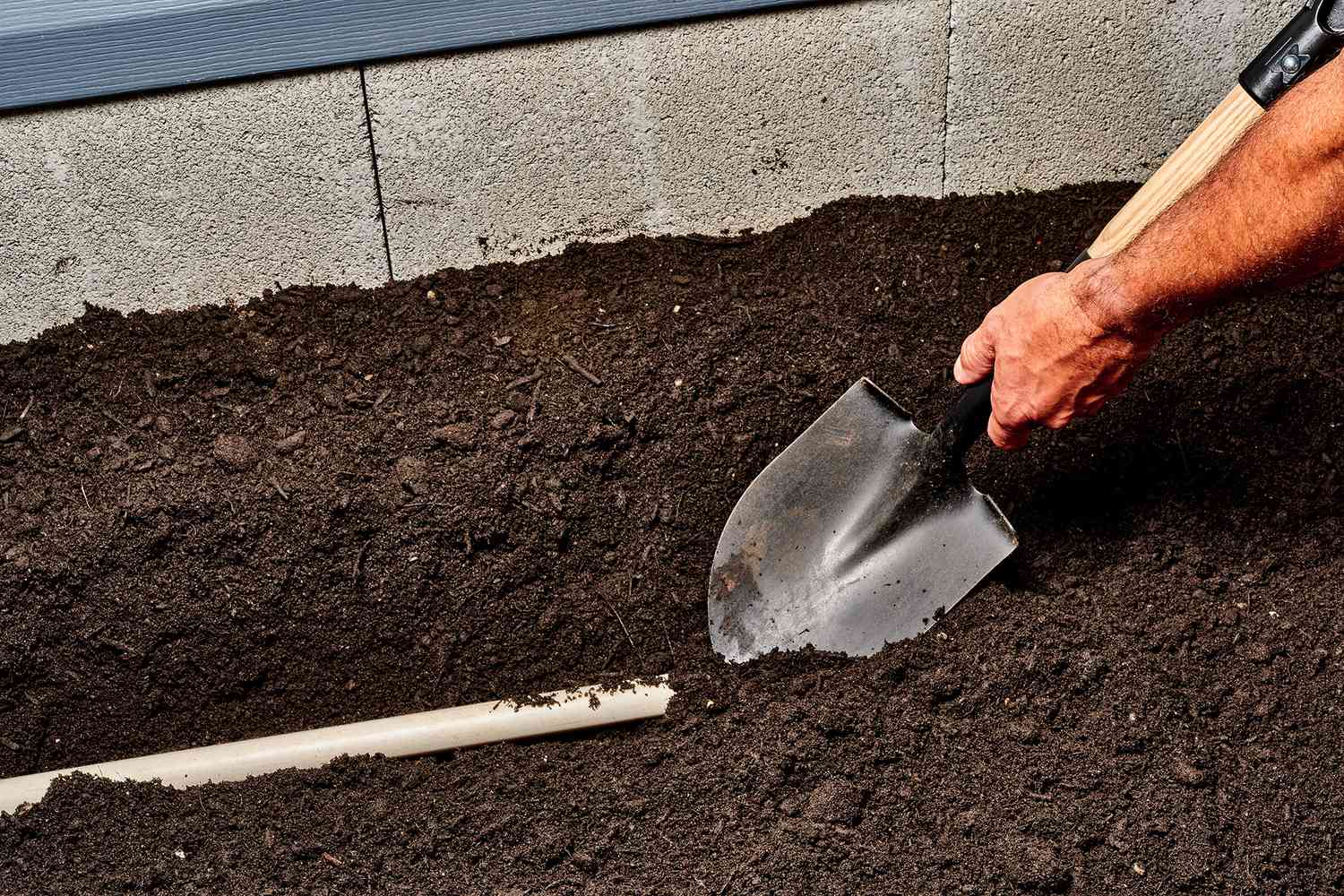 Schaufel legt Sprinklerleitungen im Boden frei