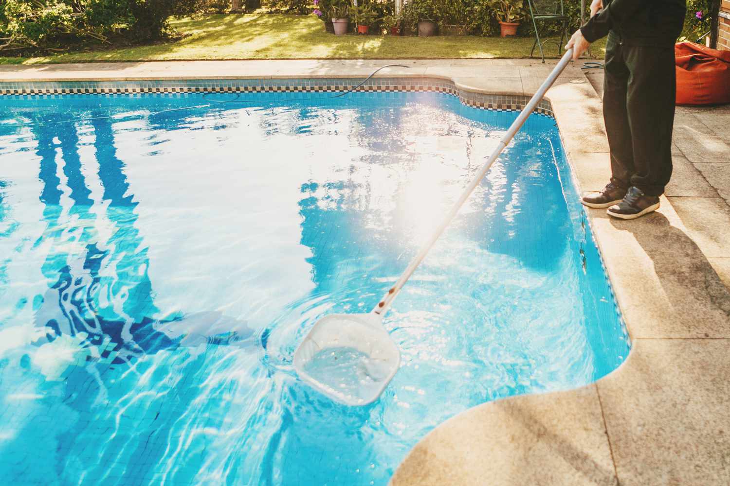 Una persona limpiando una piscina manualmente con una red