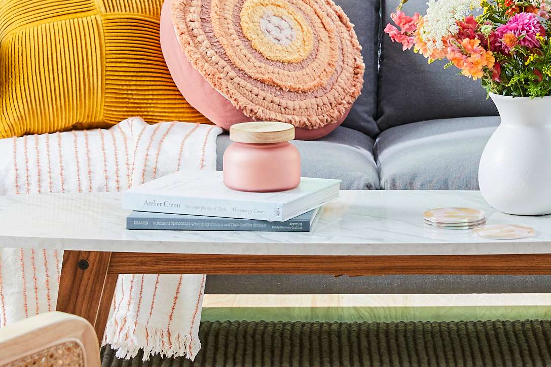 Pastel jar candle and flower vase on coffee table