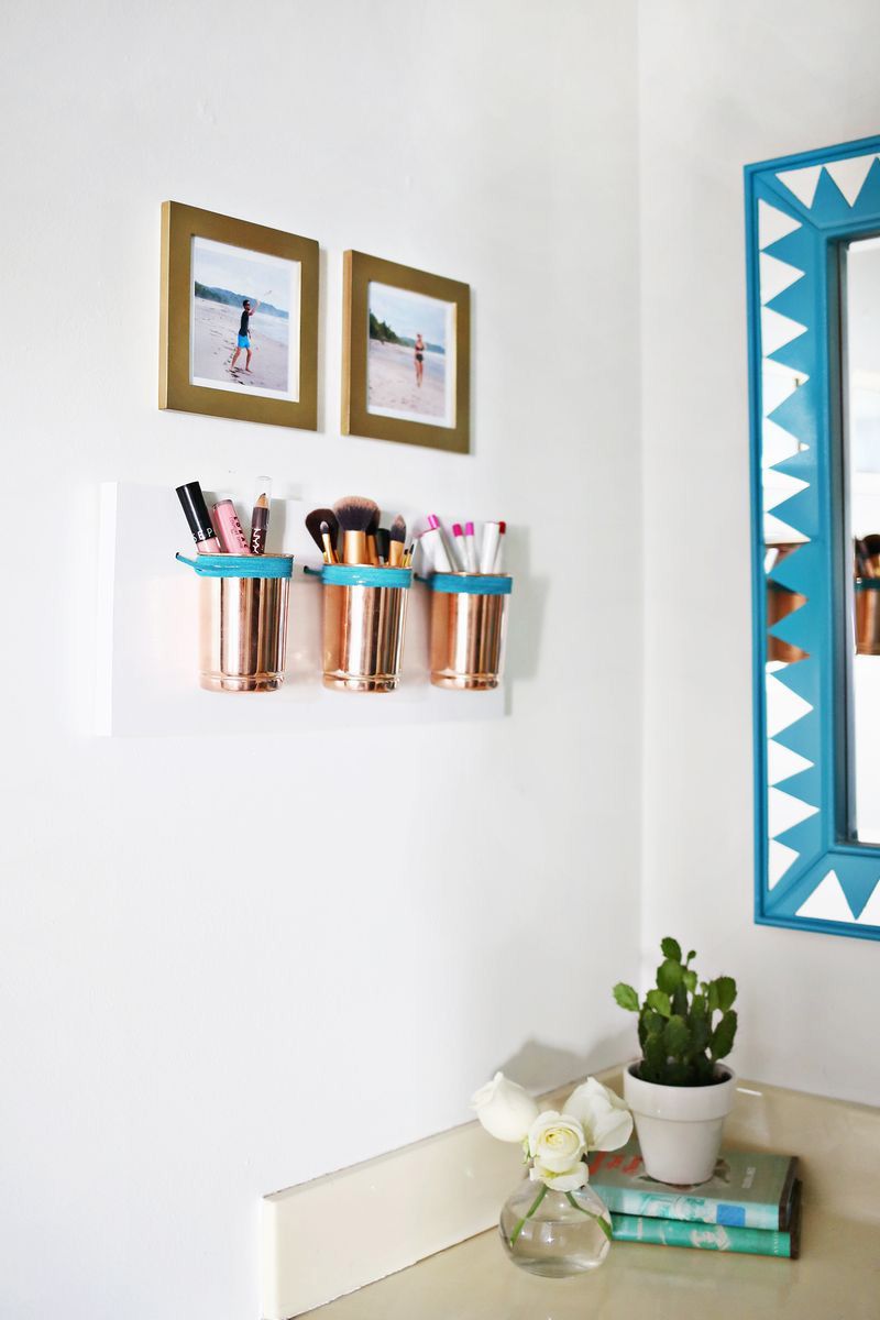 Copper and leather makeup cups on a wall in a bathroom