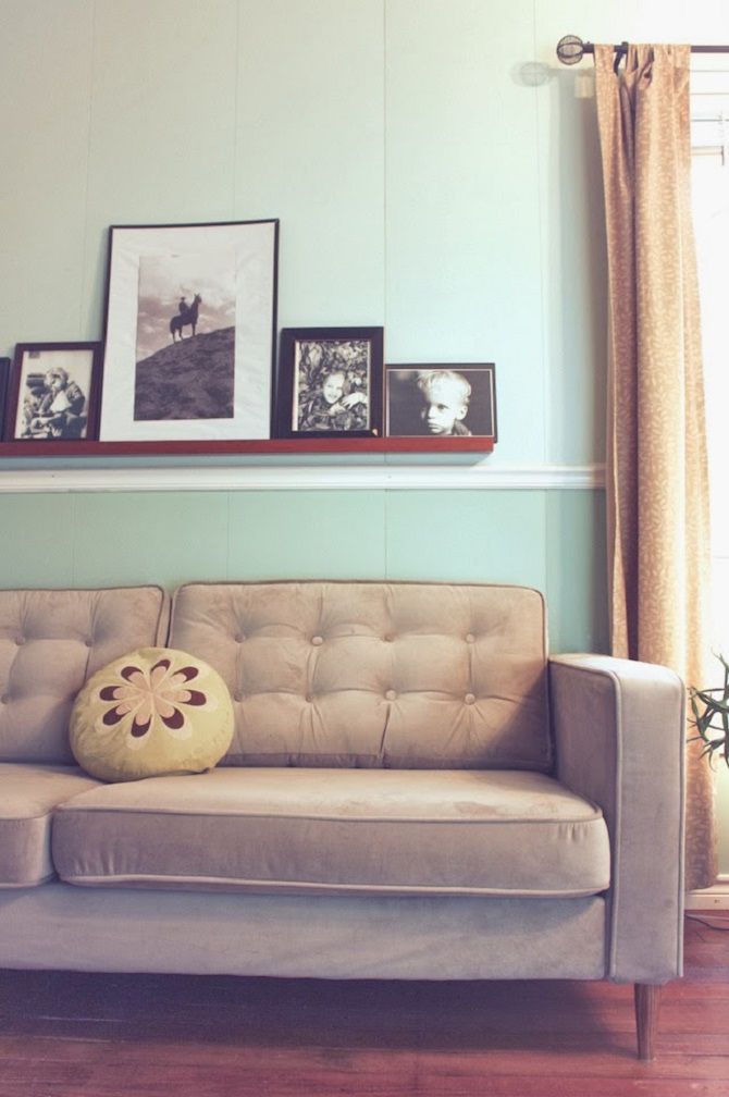 Un sofá marrón empenachado y marcos de cuadros en la pared.