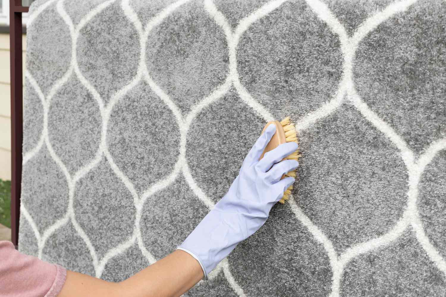 Person using a scrub brush to clean a rug