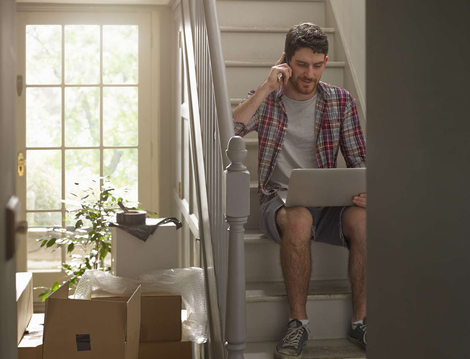 Um homem mudando de casa trabalhando no telefone e no laptop