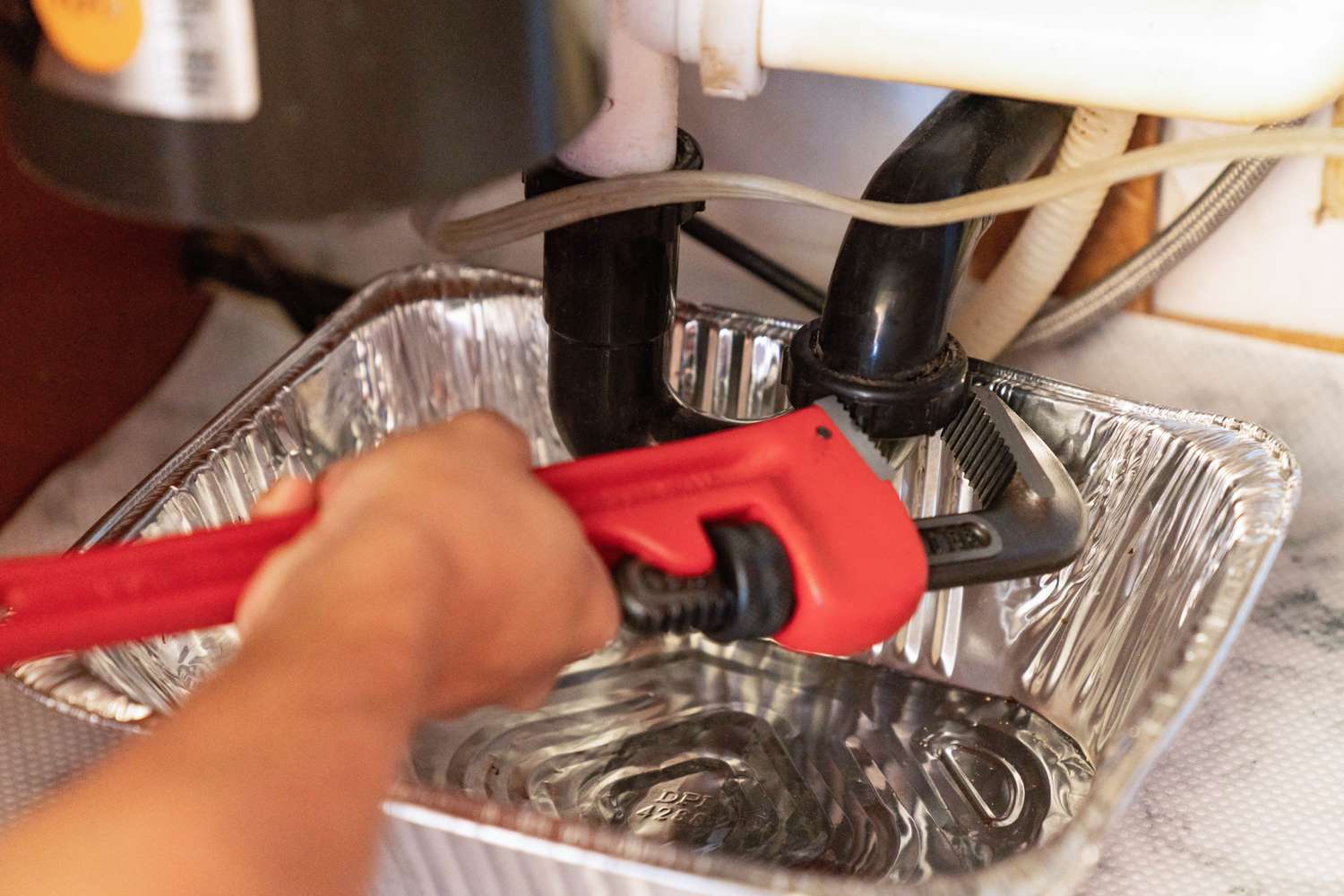 P-trap loosened with wrench under kitchen sink