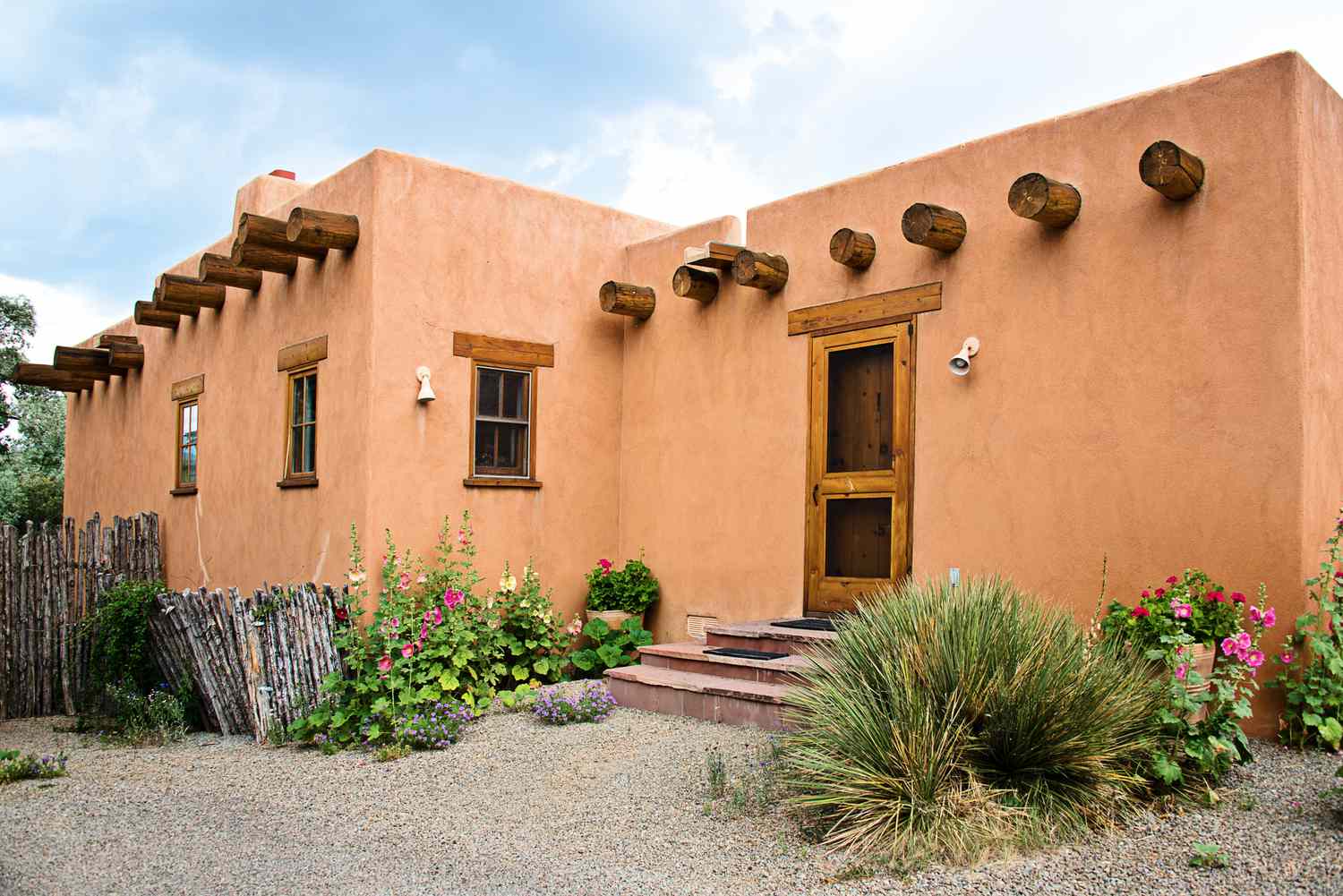 Casa de adobe de Santa Fe con muro de estuco y flores