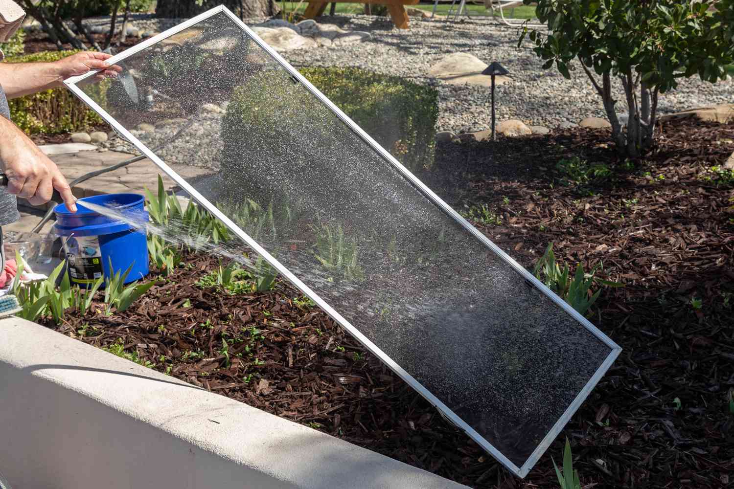 Türgitter wird mit dem Gartenschlauch auf dem Erdboden abgespült